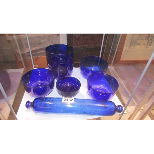 2432 - A Bristol blue glass rolling pin and seven blue glass bowls. (Collect only)