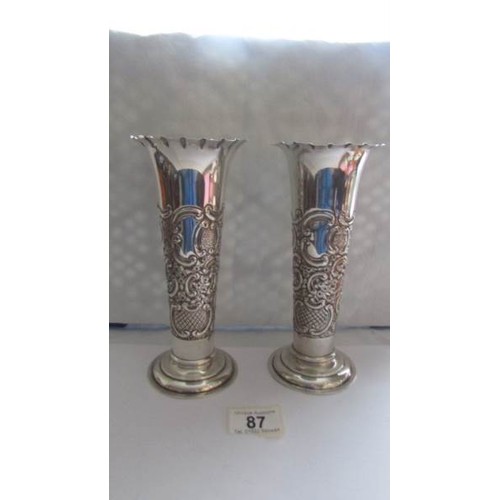 87 - A pair of silver embossed vases.