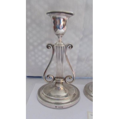 88 - A pair of lyre shaped silver candlesticks.