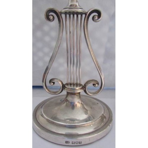 88 - A pair of lyre shaped silver candlesticks.