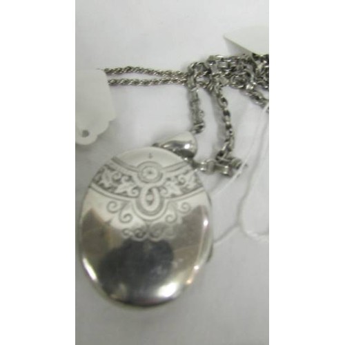 108 - A white metal locket on chain and a silver needlecase of white metal chain.