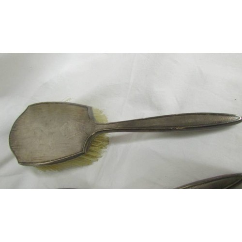 201 - A silver backed hand mirror with two matching brushes.