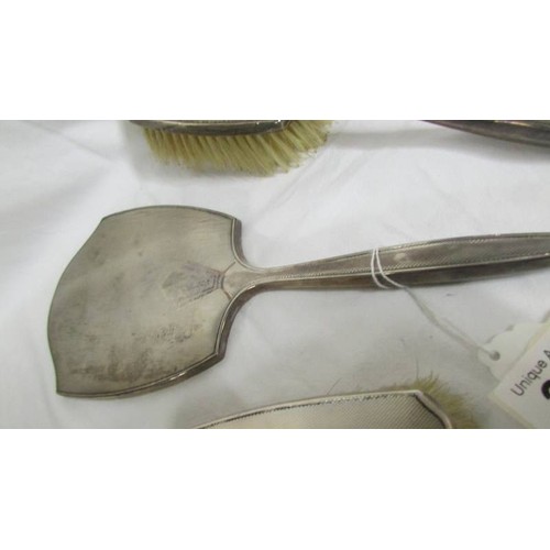 201 - A silver backed hand mirror with two matching brushes.