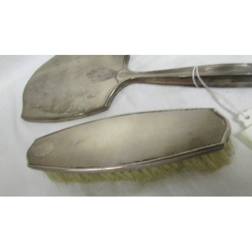 201 - A silver backed hand mirror with two matching brushes.