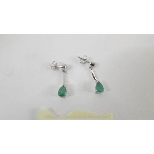 127 - A pair of white gold and emerald earrings.