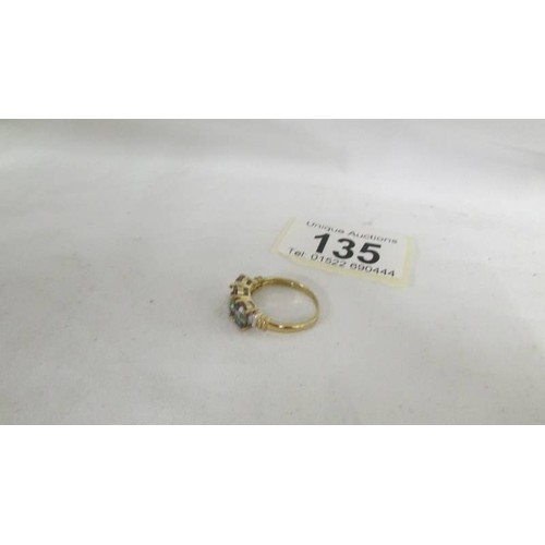 135 - A diamond and stone set ring in a 9ct gold shank in a three stone design, size O.