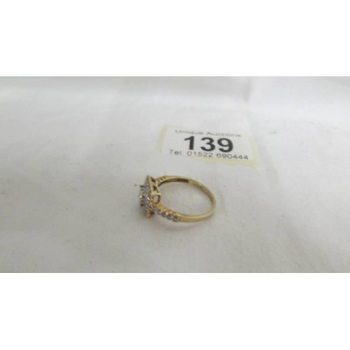 139 - A diamond ring in a square design with princess cut stones and round cut stones in 9ct gold. size R.