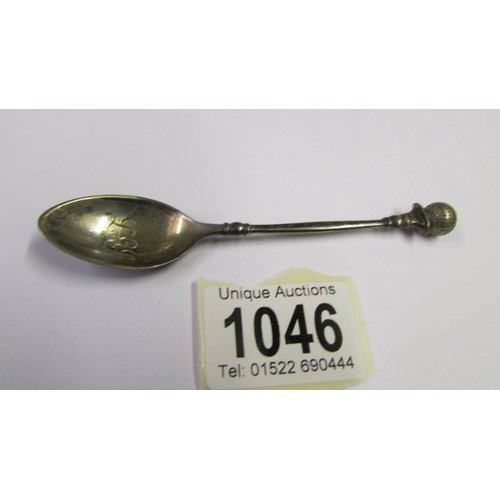 1046 - A golf related silver teapoon and another silver teaspoon.