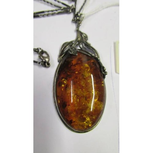 1052 - An art nouveau style silver and amber set pendant on a white metal chain.