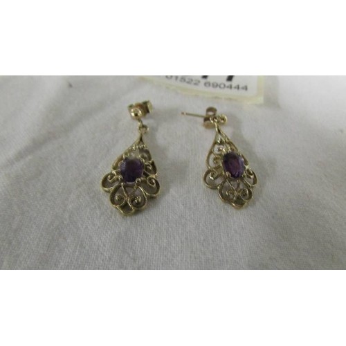 1077 - A pair of amethyst set ear pendants in gold.