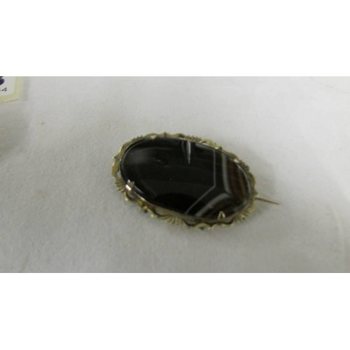 1083 - Two Victorian banded agate brooches, one in yellow metal, one in white metal.