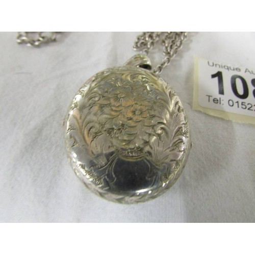 1085 - A silver engraved locket on a silver chain.