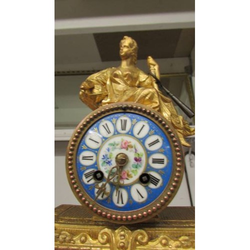 1193 - A French gilded mantel clock with porcelain panels complete with key and pendulum.