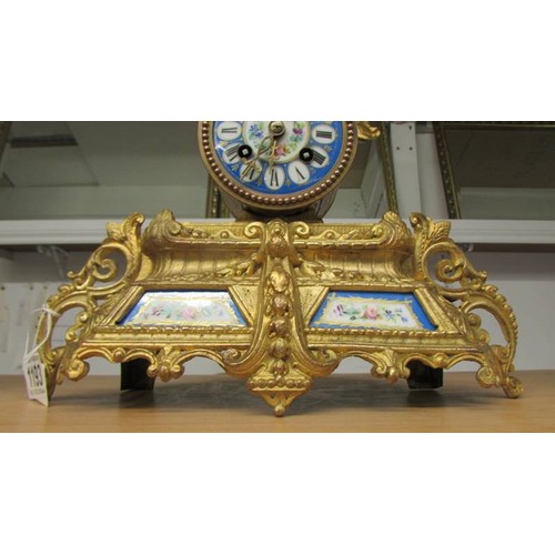 1193 - A French gilded mantel clock with porcelain panels complete with key and pendulum.