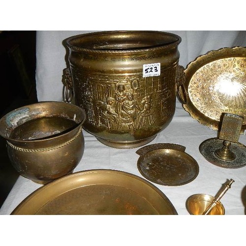 523 - An old embossed brass jardiniere and other brassware.