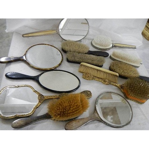 524 - A mixed lot of vintage hand mirrors and hair brushes including two with silver frames.