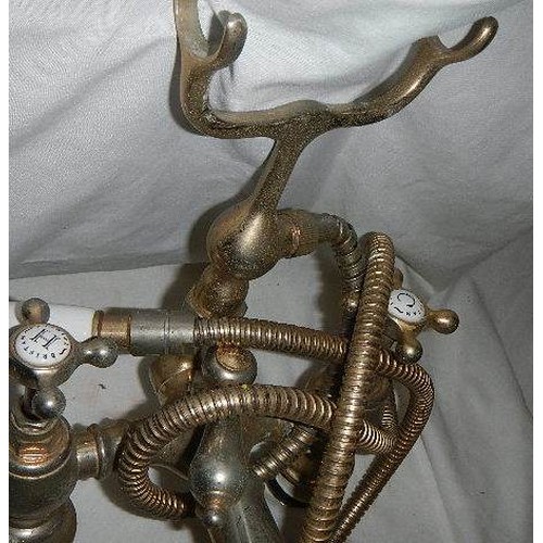 552 - A set of old brass bath taps with shower attachment.