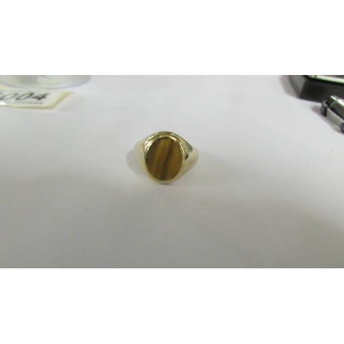 1004 - A gent's 9ct gold ring set Tiger's eye, size O. 4.4 grams.