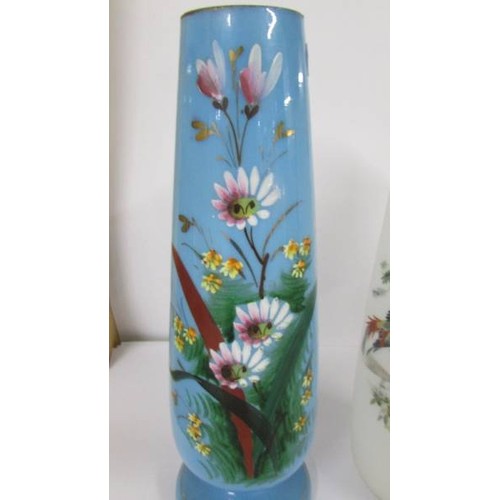 1202 - Two hand painted glass vases:- 1 blue with floral pattern and 1 opaque with birds.