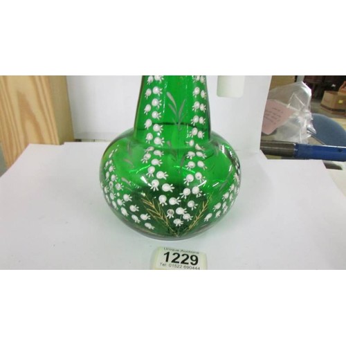 1229 - A green glass claret jug hand decorated with lily of the valley, 30cm< (a/f crack under handle).