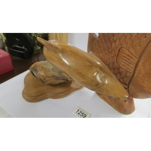 1259 - A carved wood dolphin and another carved fish.