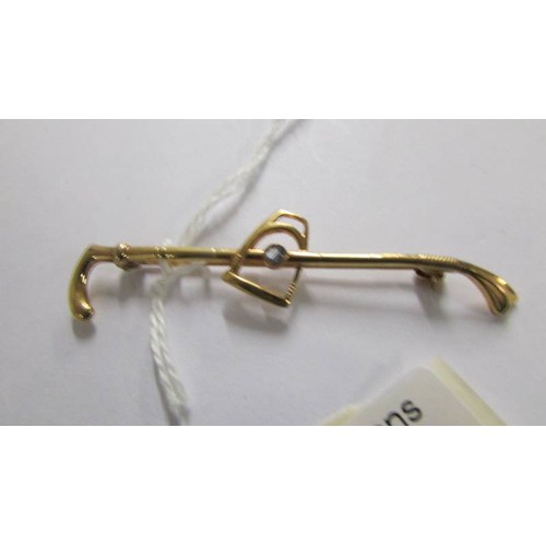 1067 - An early 20C rolled gold tie pin/brooch in the form of a riding crop and stirrup by Gustav Glinkert ... 