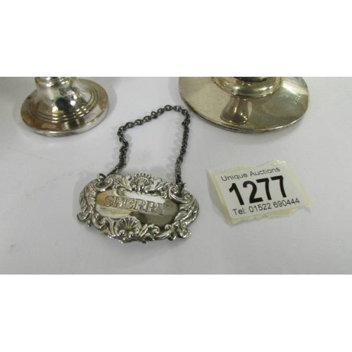 1277 - A silver candle holder, silver spill vase and silver sherry label.