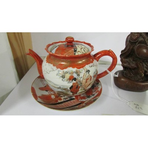 1278 - A Chinese teapot on saucer and a figure of a Buddha,