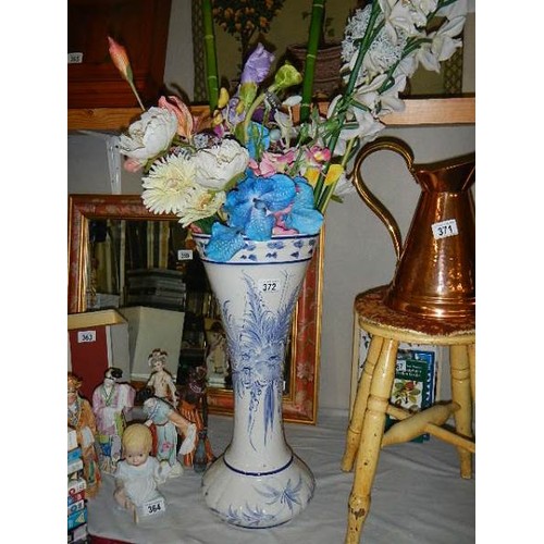 372 - A tall blue and white vase with artificial flowers.