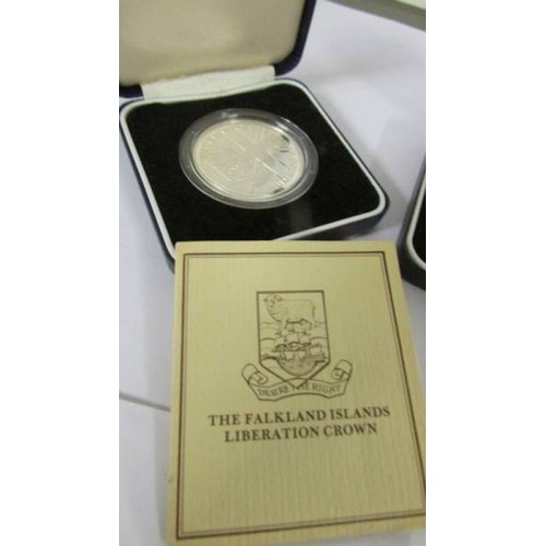 1149 - Two Cased Falkland Islands silver crowns, Liberation and 150th anniversary, with certificates.