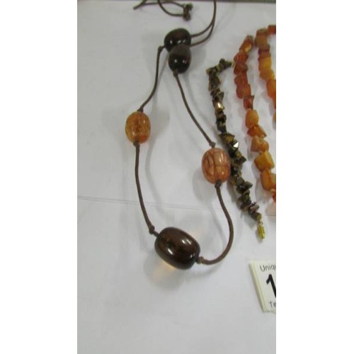 1077 - A natural amber necklace in a cube design, a further necklace and a tiger eye stone bracelet.