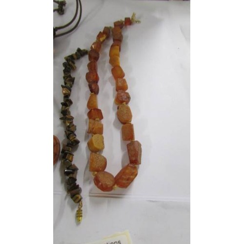 1077 - A natural amber necklace in a cube design, a further necklace and a tiger eye stone bracelet.