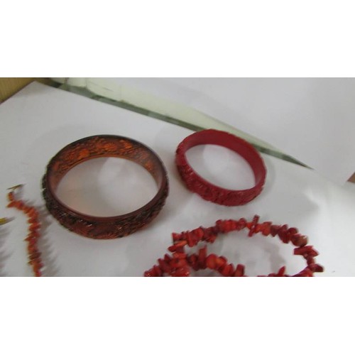 1078 - A red coral necklace, a pink coral necklace, two bangles and a similar ring.