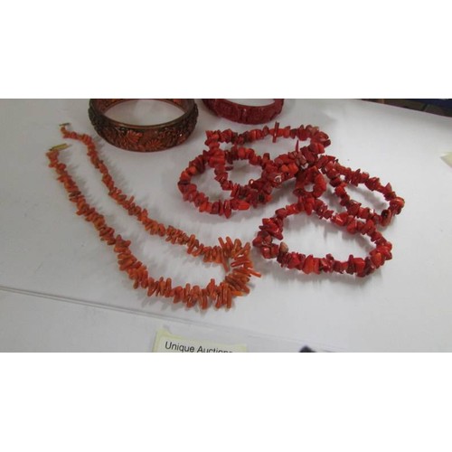 1078 - A red coral necklace, a pink coral necklace, two bangles and a similar ring.