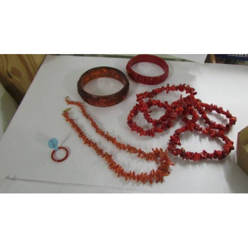 1078 - A red coral necklace, a pink coral necklace, two bangles and a similar ring.