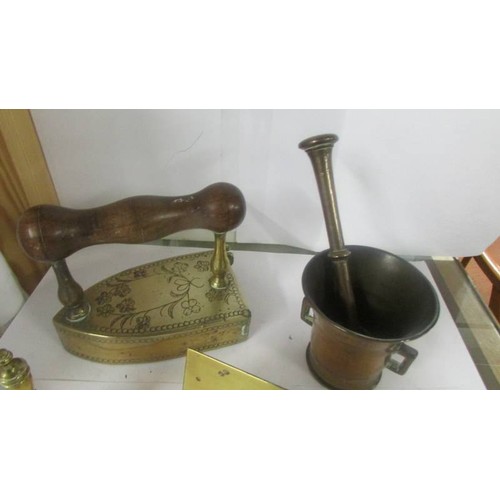 1395 - A brass pestle & mortar, a brass flat iron, a brass bell and a brass door sign.