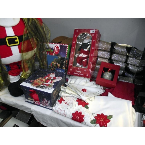 39 - A selection of Christmas items including tablecloth, napkins, singing Santa, Christmas box etc COLLE... 