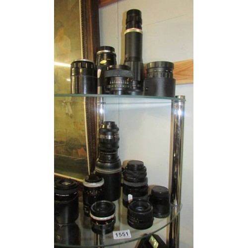 1551 - Two shelves of vintage camera lenses.