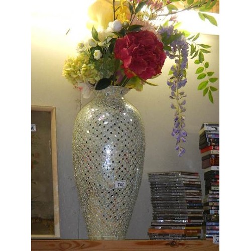 747 - A tall silver coloured vase with faux flowers. COLLECT ONLY.