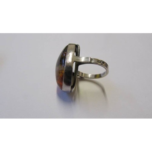 208 - A large silver ring with large amber coloured stone in art deco design.