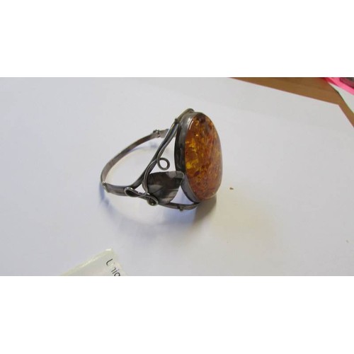 229 - A silver bangle with large amber coloured stone.