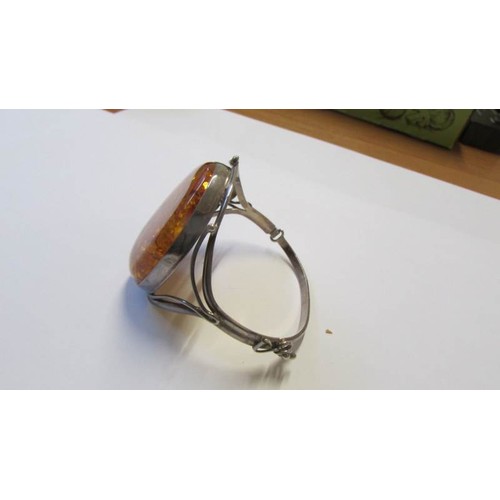 229 - A silver bangle with large amber coloured stone.