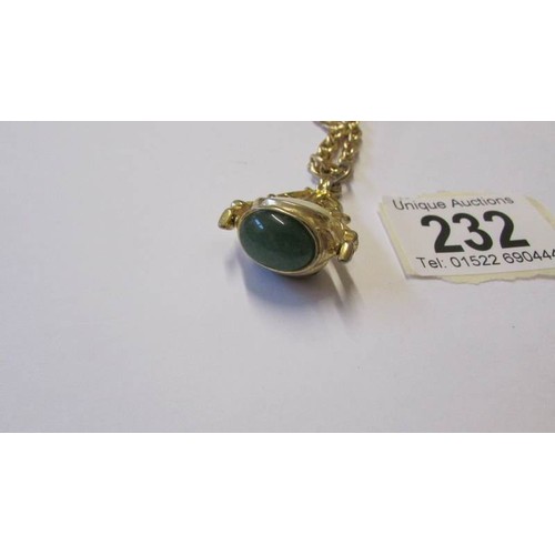 232 - A yellow metal fob set three stones including Tigers eye and mother of pearl.