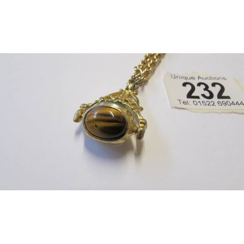 232 - A yellow metal fob set three stones including Tigers eye and mother of pearl.