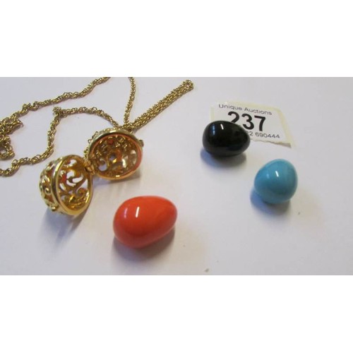 237 - A Yellow metal opening egg pendant on chain with three interchangable coloured eggs, marked Joan Riv... 