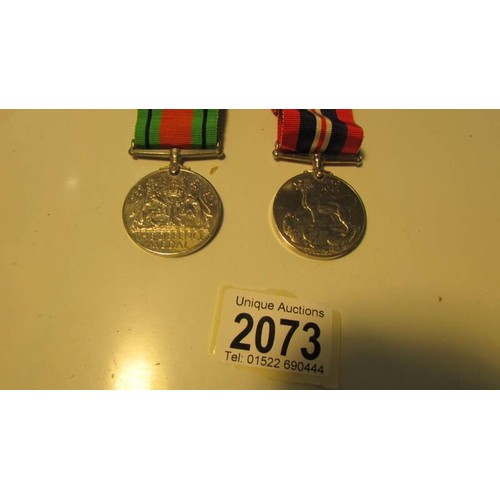 2073 - A Defence medal with ribbon, a 1939-45 war medal with ribbon, Mr J K Steel, 353/22673.