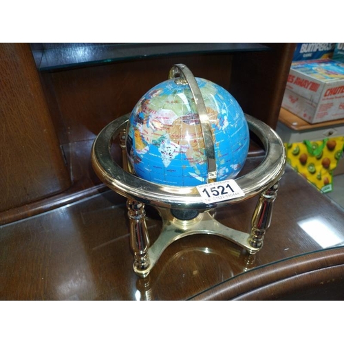 1521 - A stone globe on brass effect stand. 14cm diameter.