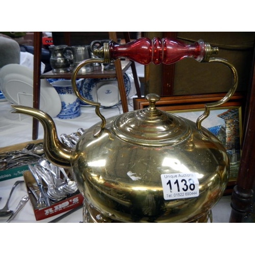 1138 - An early 20th century brass kettle on stand with cranberry glass handle