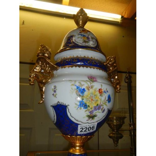 2206 - A porcelain lidded urn on metal base.