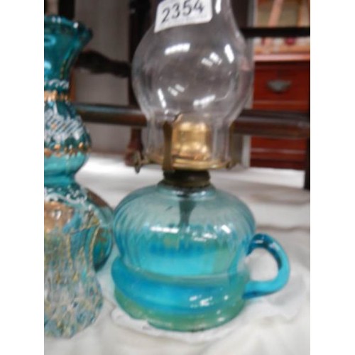 2354 - A Victorian blue glass hand oil lamp, a blue glass vase and a small vase.